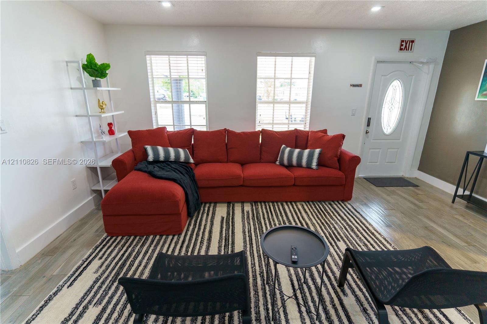 Wood-finish flooring, recessed lighting, dual windows with blinds, and an exterior door featuring an oval glass insert