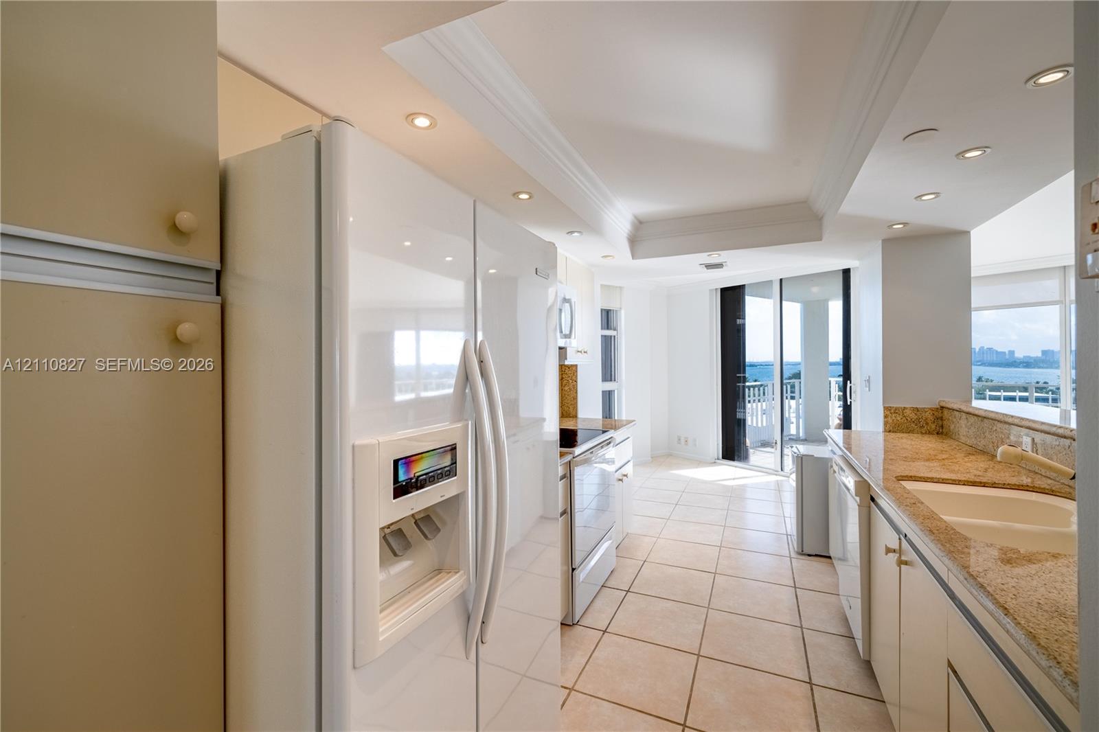 Kitchen featuring recessed lighting, stone countertops, integrated cabinetry, white appliances, and ceramic tile flooring