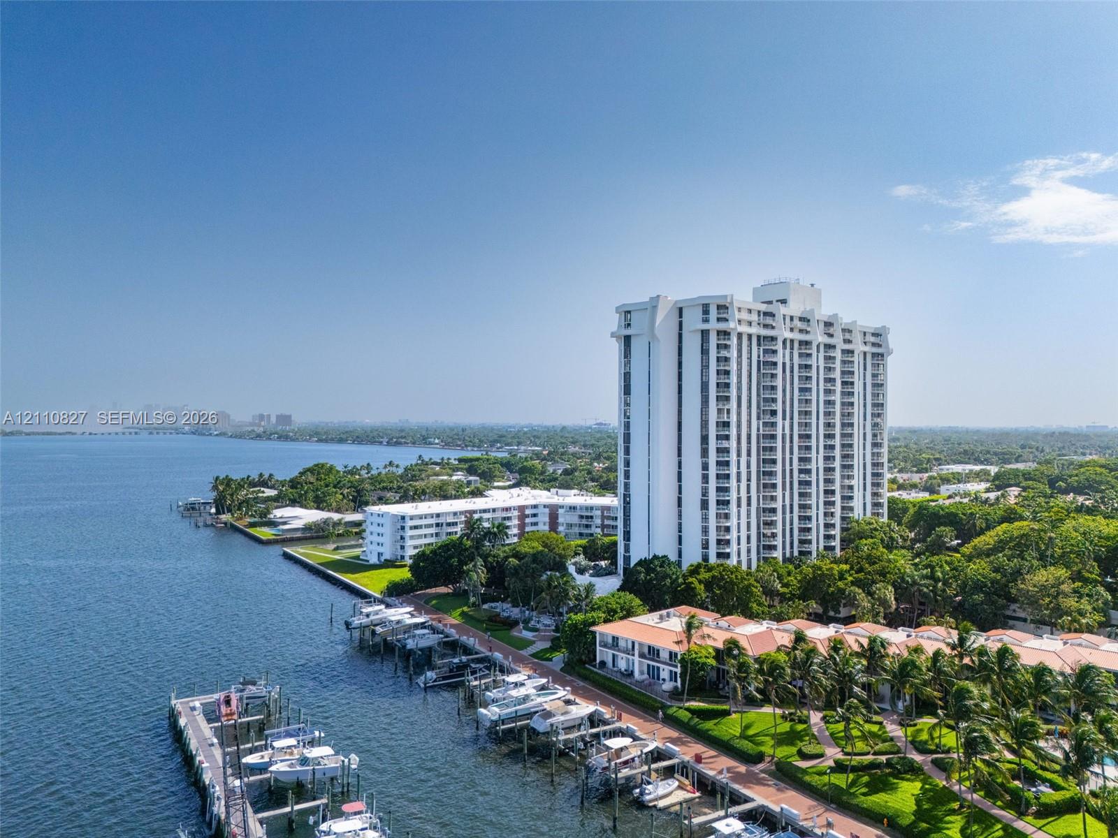 High-rise residential building featuring private boat slips, manicured landscaping, paved walkways, and direct water frontage