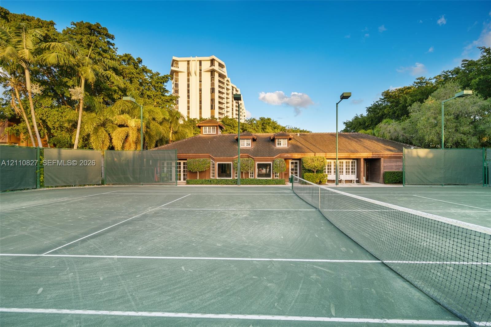 Tennis court featuring a hard surface, perimeter fencing, and integrated court lighting