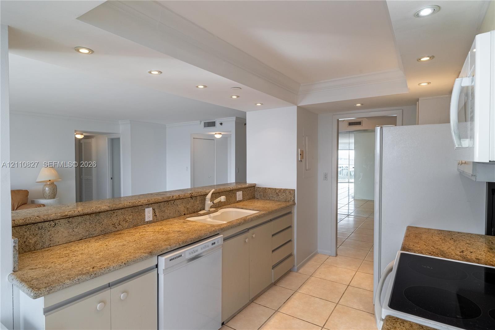 Kitchen featuring stone-finish countertops, tile flooring, recessed ceiling lighting, a built-in dishwasher, and a pass-through breakfast bar