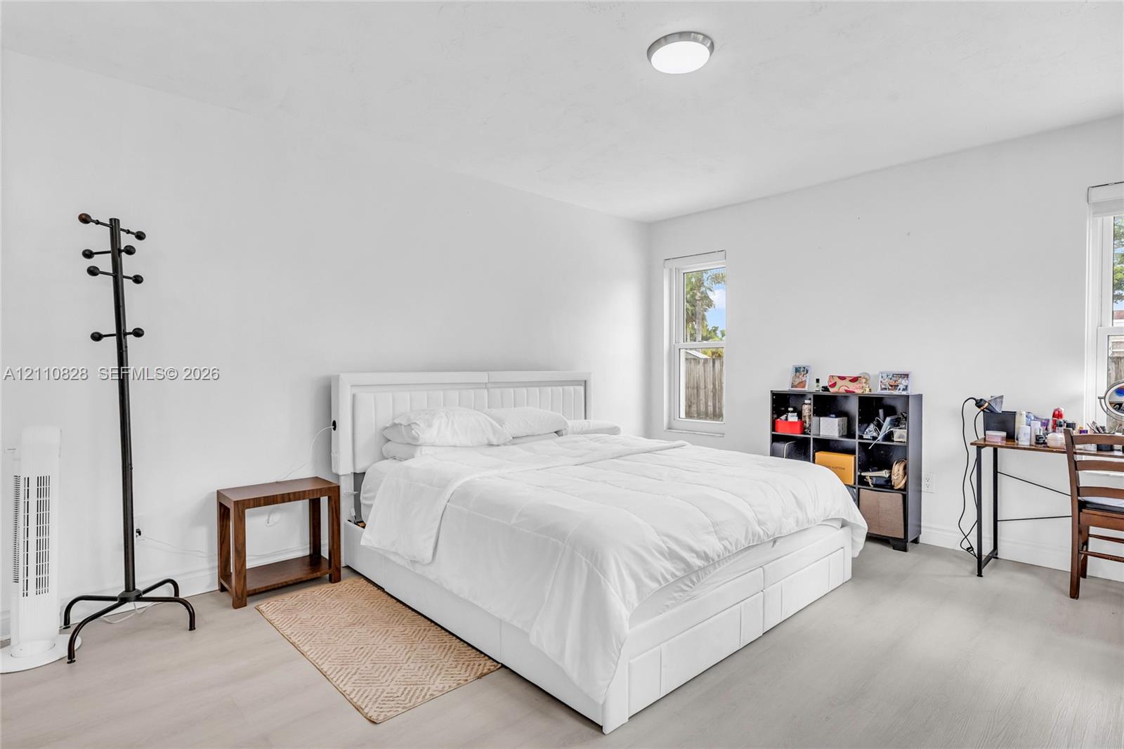 Neutral-toned wood-finish flooring, two double-hung windows, and a flush-mount overhead light fixture