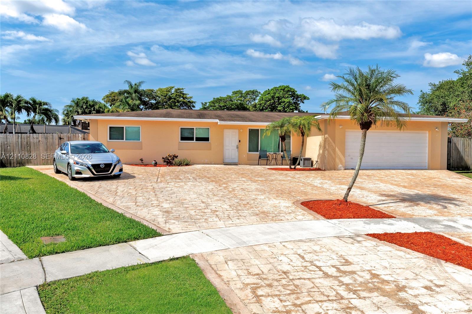 Single-story residence featuring a stamped concrete driveway, two-car garage, manicured lawn, and mature palm landscaping