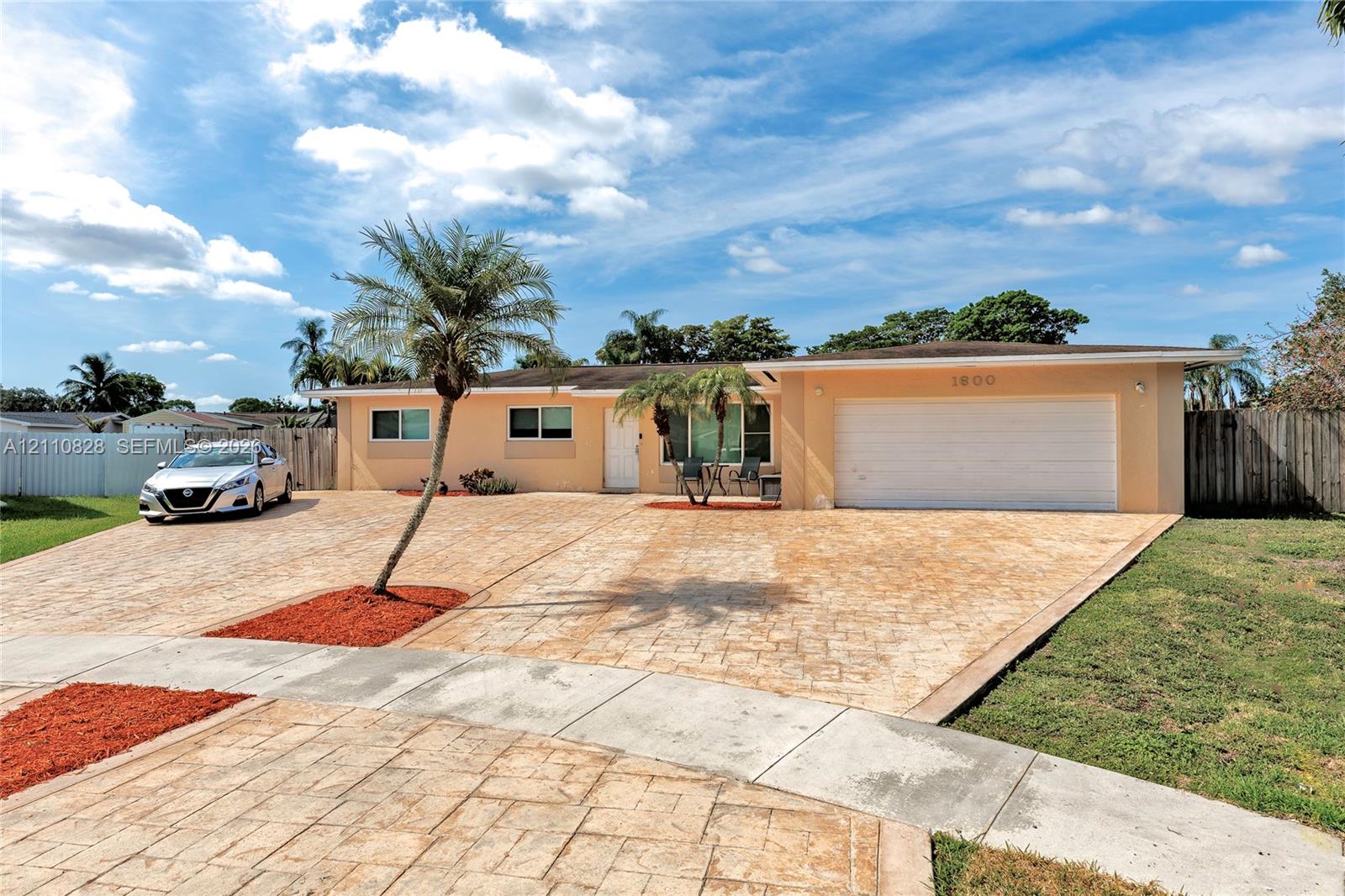 Single-story exterior featuring a stamped concrete driveway, two-car garage, and palm-accented landscaping
