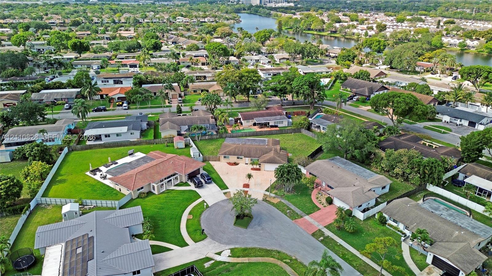 Aerial perspective of a cul-de-sac residential location featuring expansive corner lots, multi-pitched shingle roofing, paved driveways, and established mature landscaping