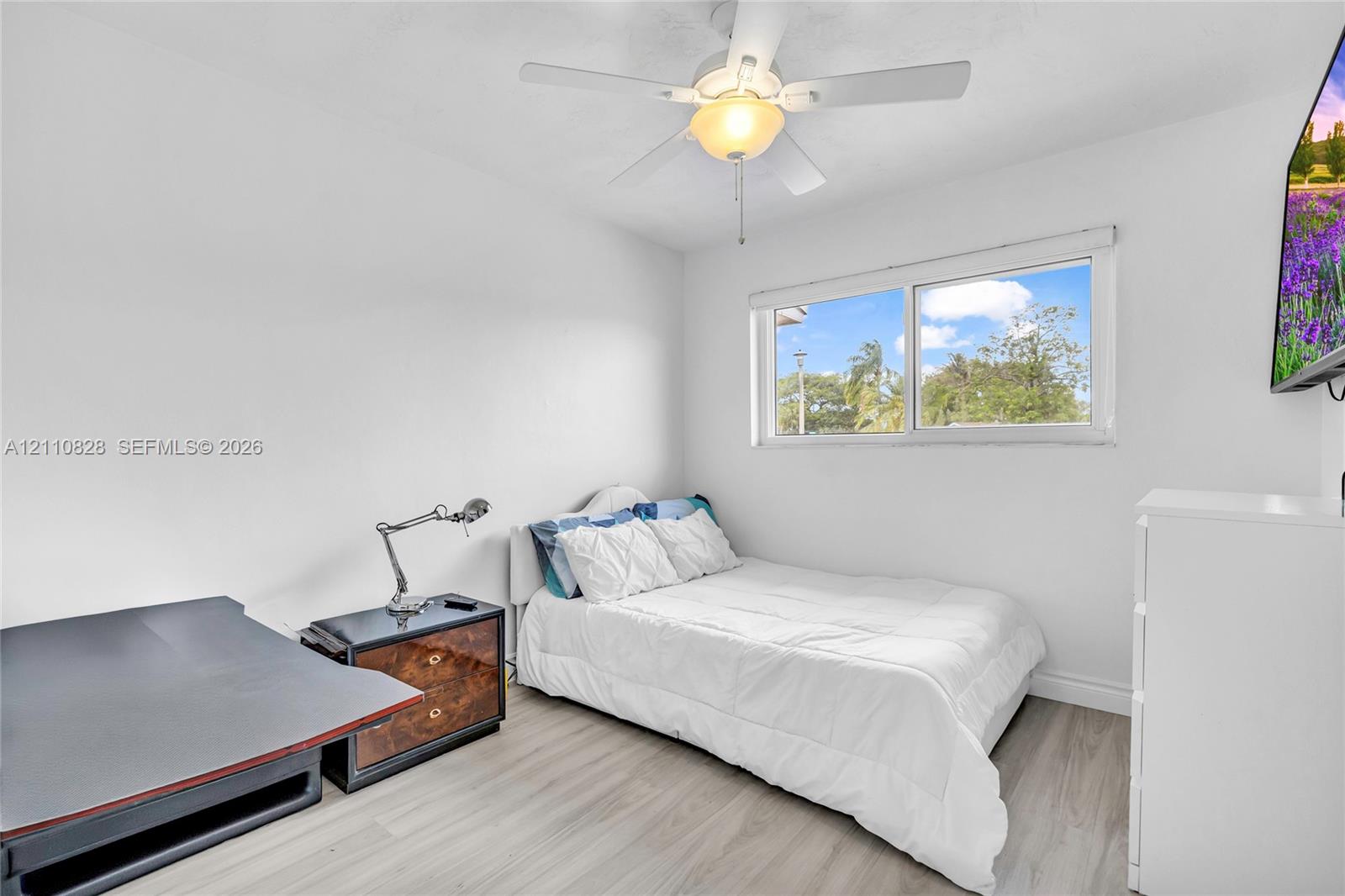 Neutral interior featuring wood-finish flooring, a ceiling fan with integrated lighting, and a horizontal sliding window