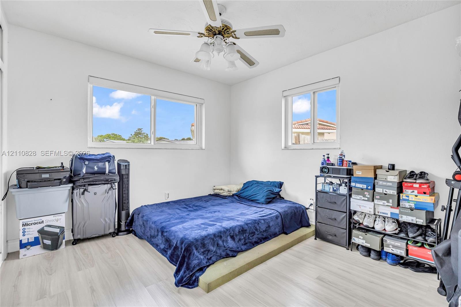 Neutral-toned wood-finish flooring, dual sliding-sash windows, and a multi-blade ceiling fan with integrated lighting