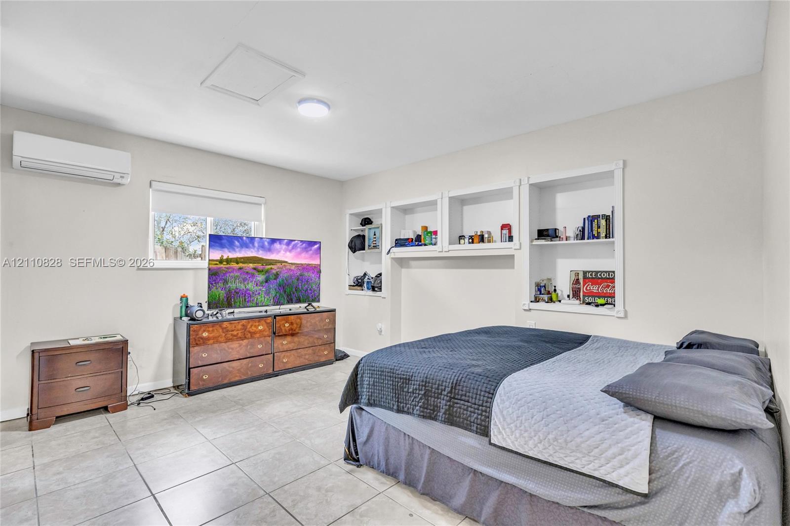 Neutral interior featuring tile flooring, wall-mounted air conditioning unit, and built-in recessed shelving