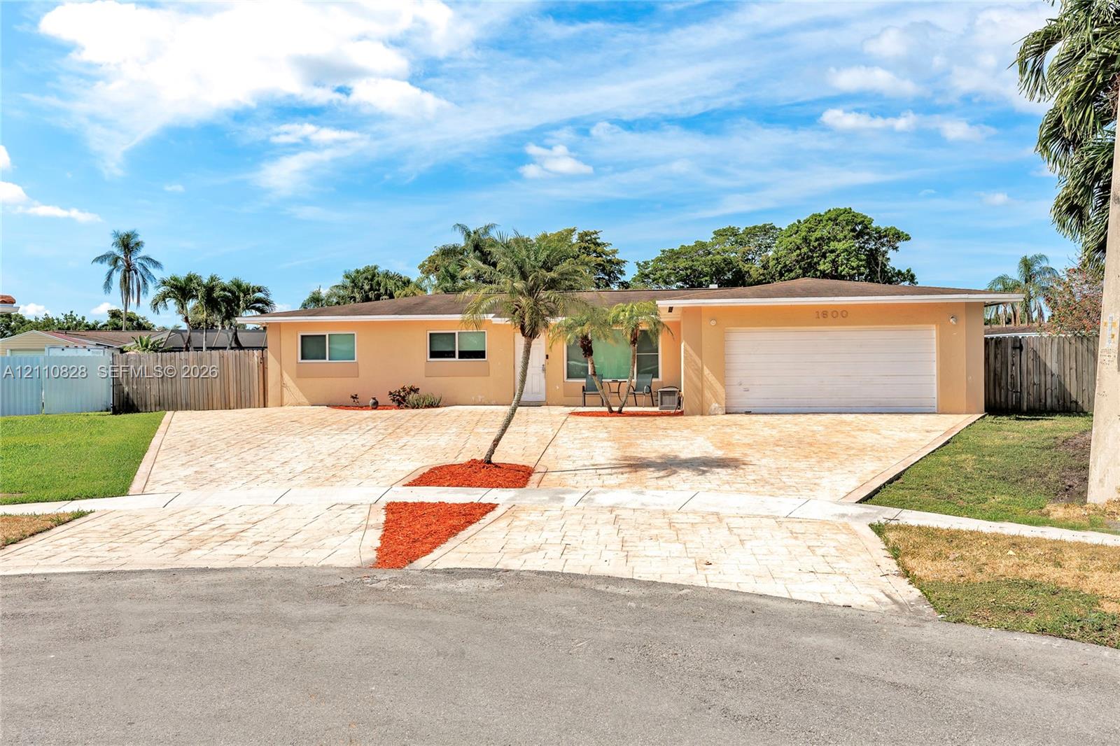 Single-story residence featuring a textured paved driveway, attached two-car garage, and neutral exterior finish