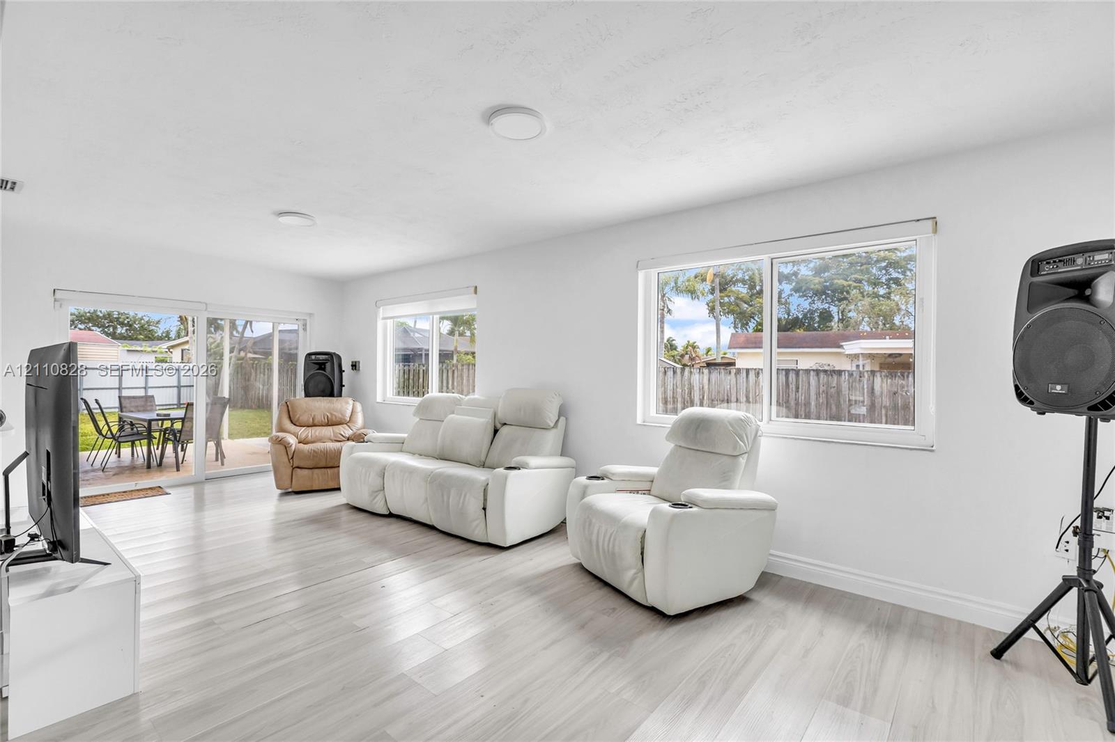 Living area featuring light-toned wood-finish flooring, white walls, flush-mount ceiling lighting, and horizontal sliding windows