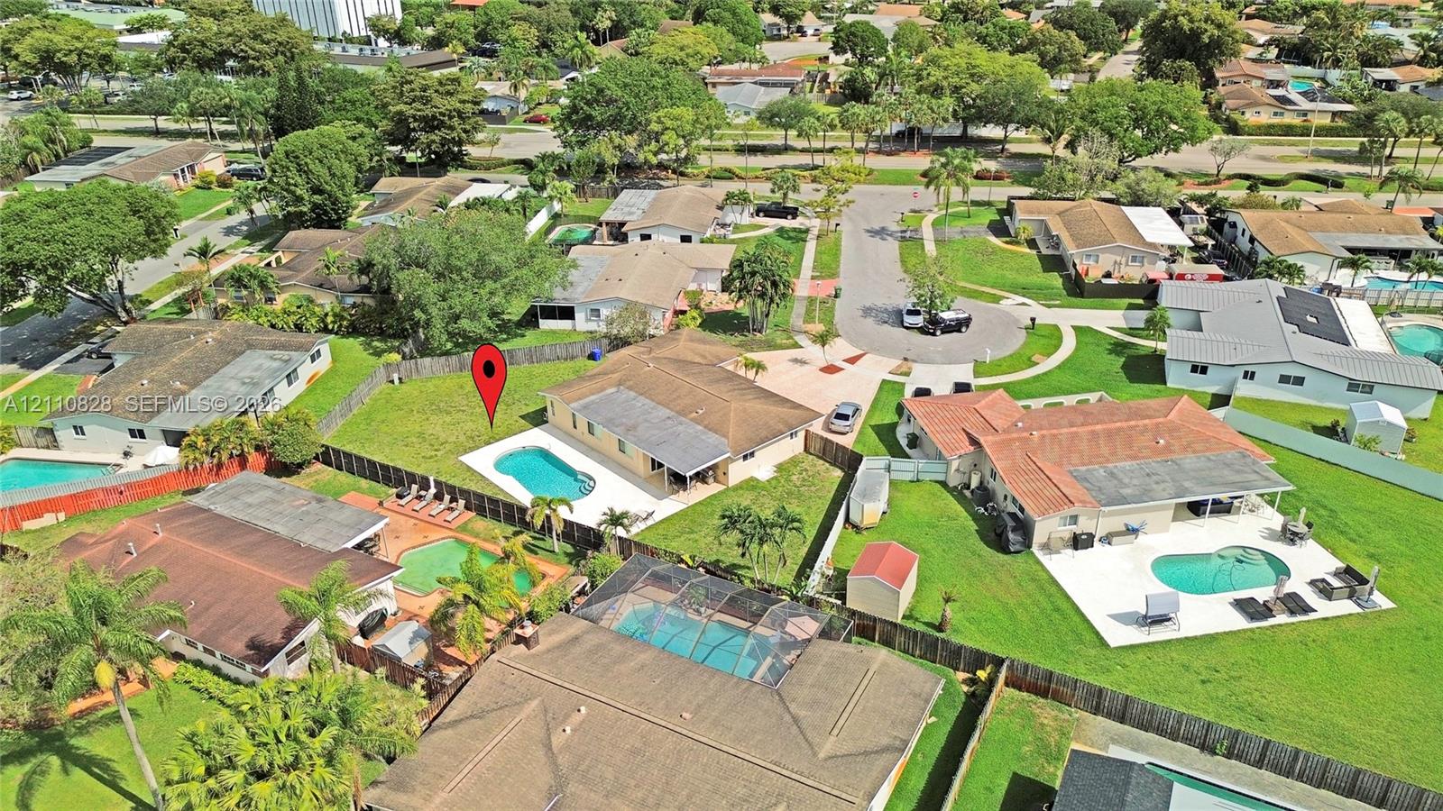 Aerial perspective of a single-story residence featuring a concrete-tiled hip roof, an in-ground swimming pool, a concrete patio, and a fenced backyard