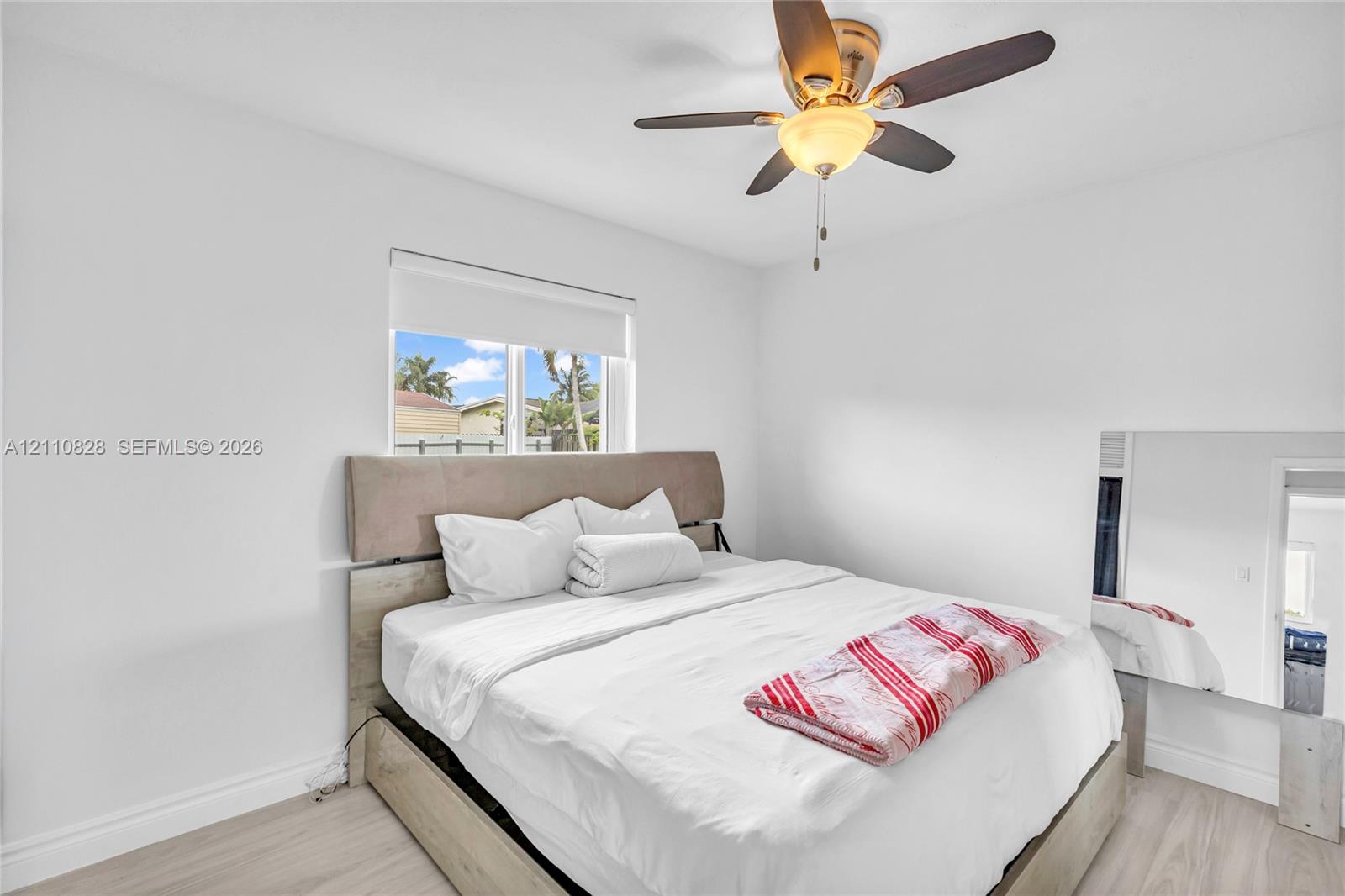 Light-filled room featuring wood-finish flooring, a neutral color palette, and an integrated ceiling fan with light fixture