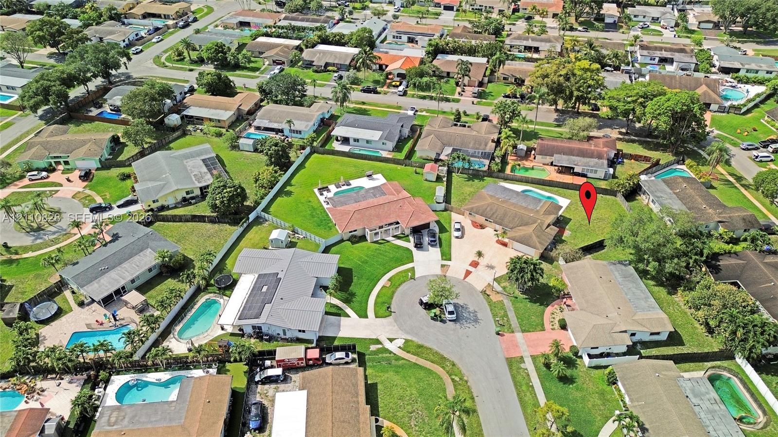 Aerial perspective featuring a residential property with a multi-hipped roofline, an attached multi-car garage, and a private rear swimming pool situated on a spacious corner lot