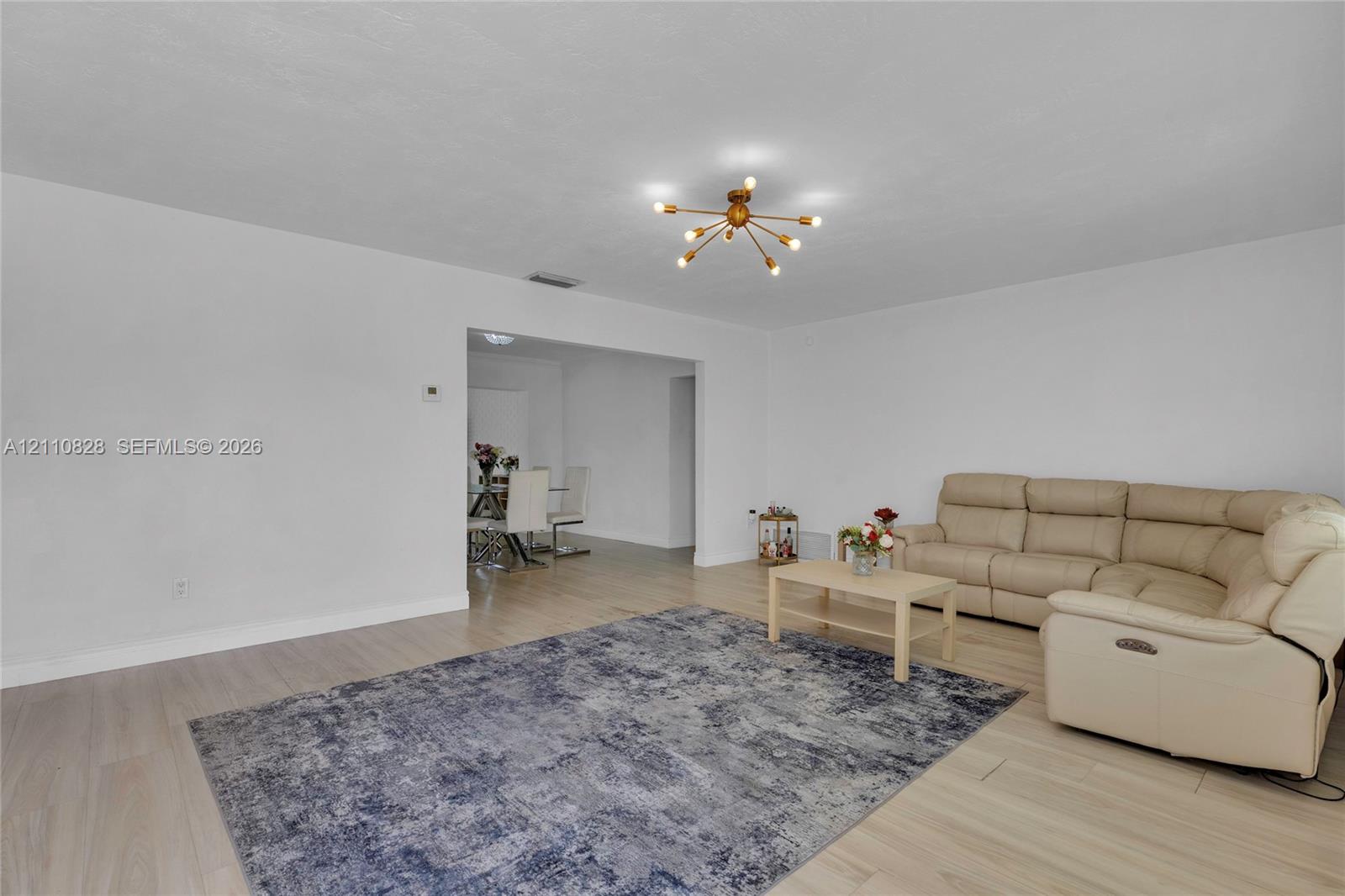 Living area featuring light-toned wood-finish flooring and a multi-arm geometric ceiling fixture