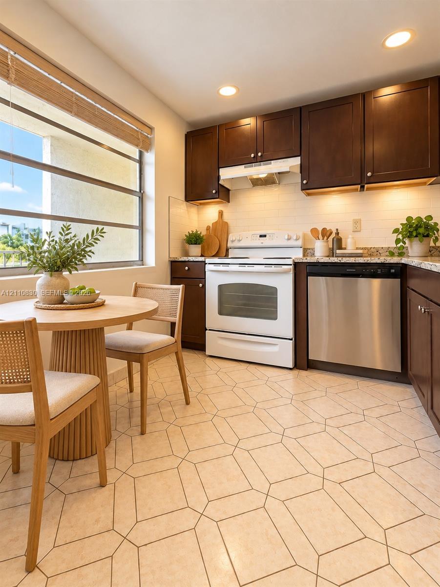 Kitchen featuring dark wood cabinetry, light-toned stone-finish countertops, geometric-patterned tile flooring, recessed ceiling lighting, and stainless steel dishwasher