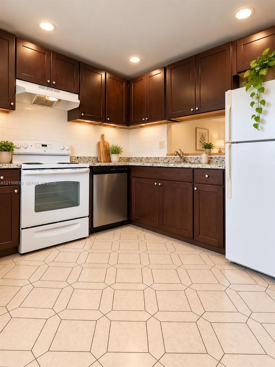 STAGED Kitchen featuring dark wood cabinetry, light stone-finish countertops, white subway tile backsplash, stainless steel dishwasher, and patterned tile flooring STAGED Kitchen featuring dark wood cabinetry, light stone-finish countertops, white subway tile backsplash, stainless steel dishwasher, and patterned tile flooring
