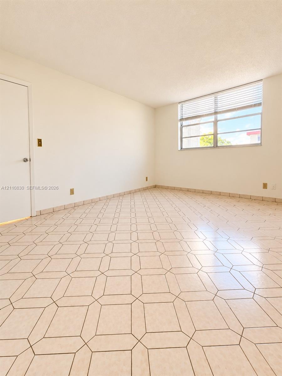 Neutral-toned geometric tile flooring and expansive single-pane window featuring horizontal blinds