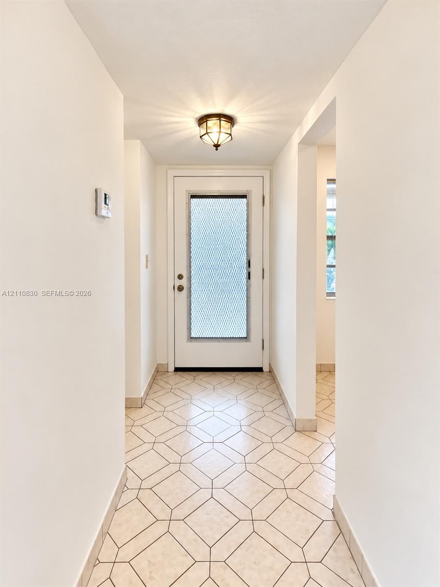 Entryway featuring geometric patterned tile flooring, a door with a metal security screen, and a flush-mount overhead light fixture