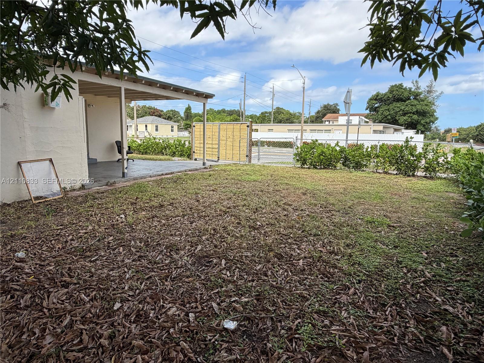 Backyard featuring a covered concrete patio, ground-level sod, and wood-paneled privacy fencing