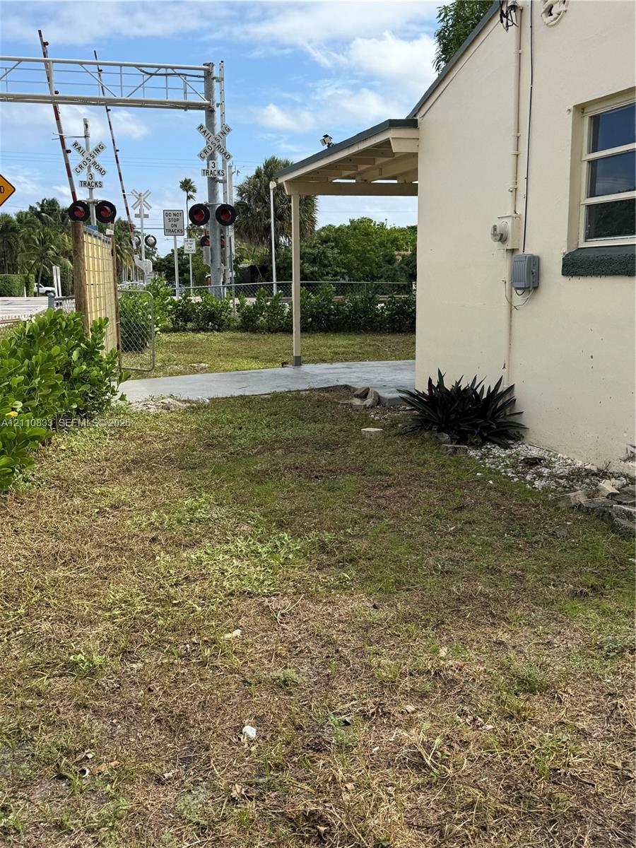 Exterior side yard featuring a concrete patio, covered porch area, and perimeter shrubbery
