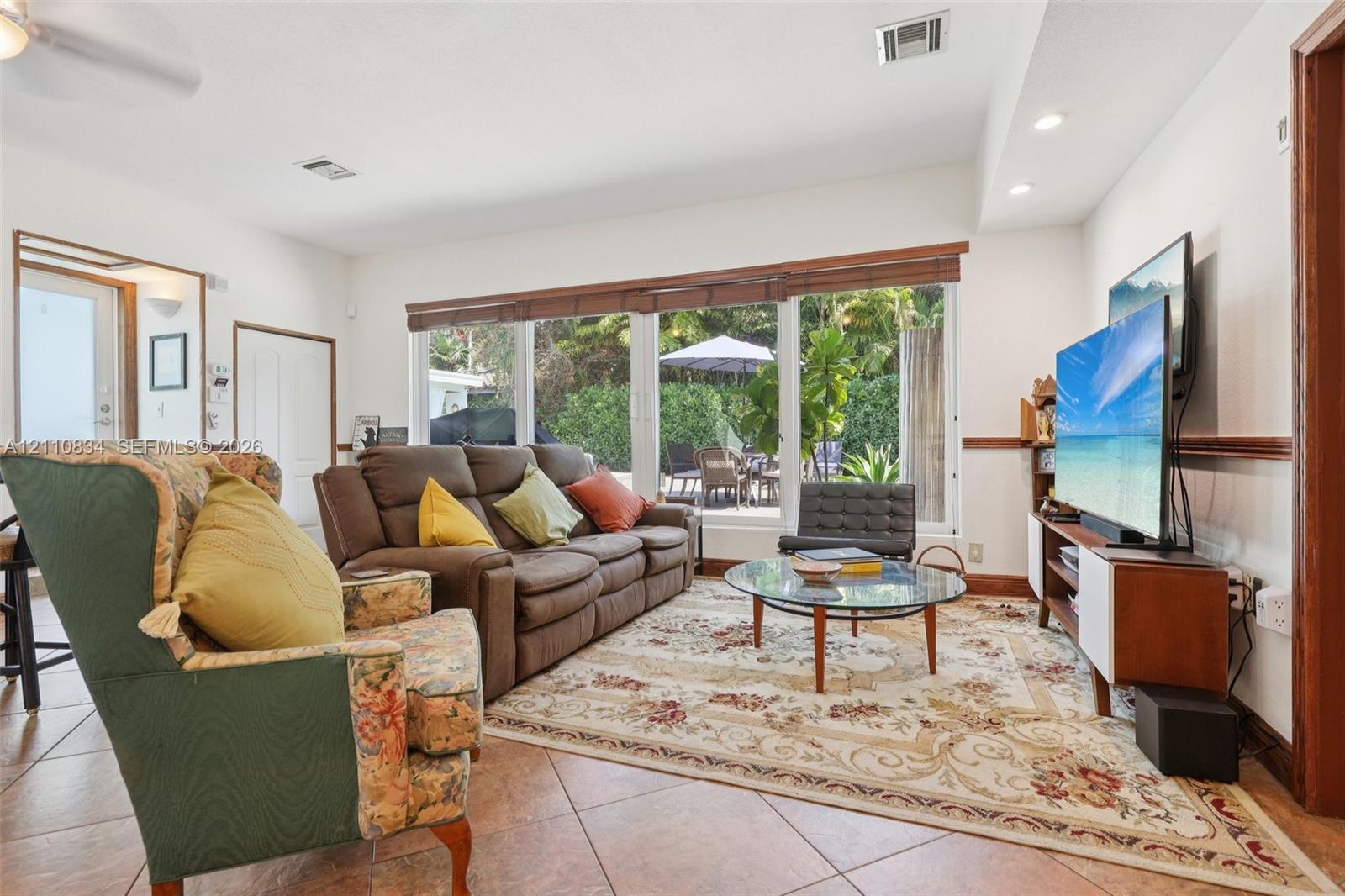 Living area featuring large-format ceramic tile flooring, recessed lighting, and a panoramic window wall with wood-slat blinds