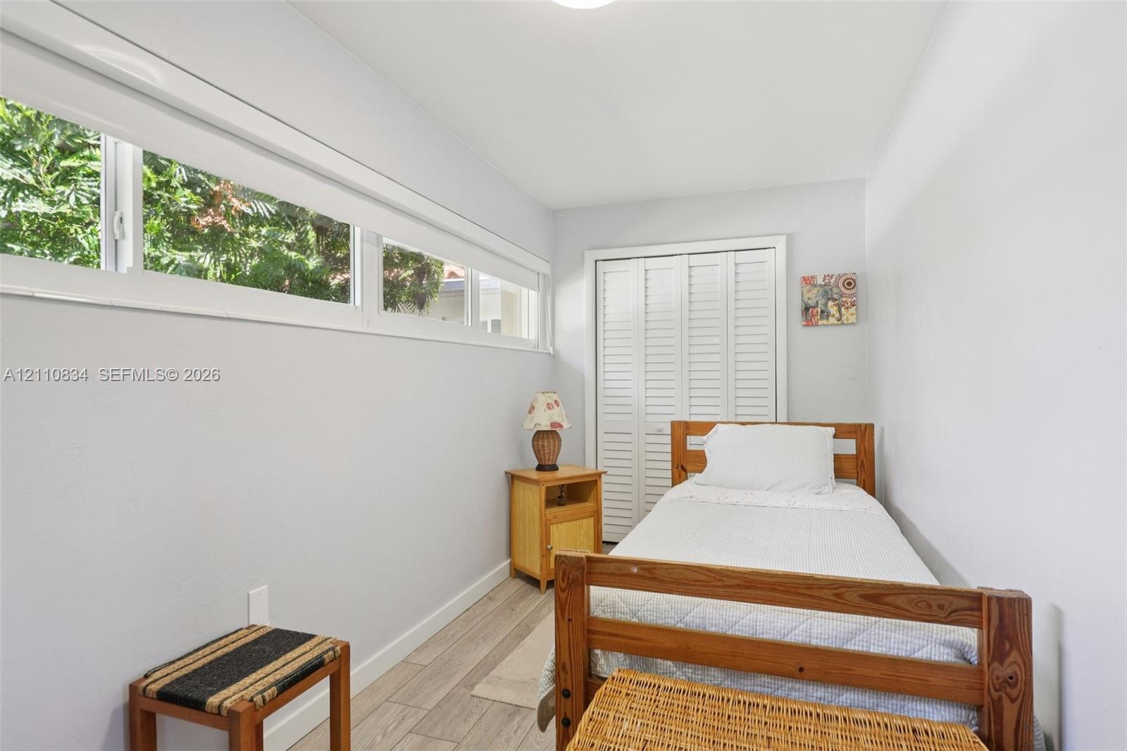 Room featuring wood-finish tile flooring, horizontally aligned windows, and louvered-panel closet doors