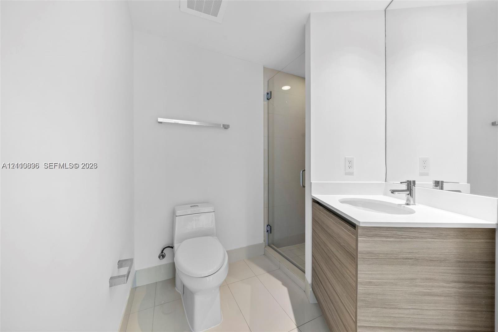 Modern bathroom featuring a floating wood-finish vanity with an integrated sink and chrome faucet, white quartz countertop, large mirror with integrated lighting, and a walk-in shower with glass enclosure