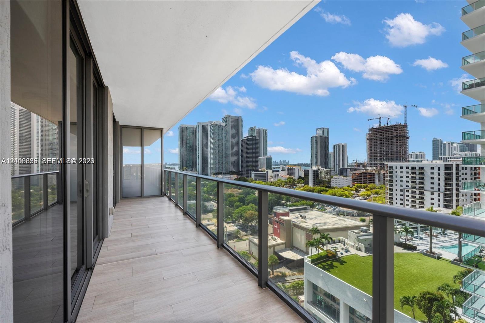 Covered outdoor balcony featuring tile flooring and a glass railing with a metal frame