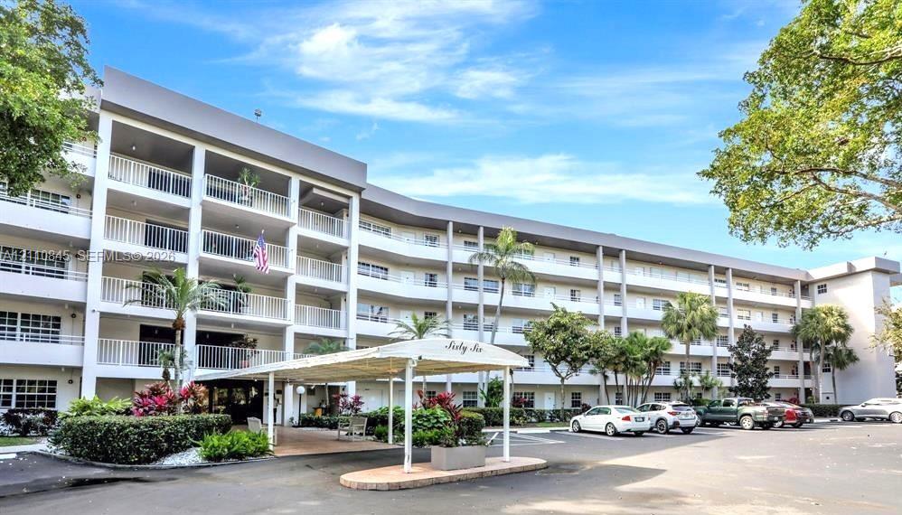 Multi-story residential building featuring covered porte-cochre entry, private balconies, and mature palm landscaping Multi-story residential building featuring covered porte-cochre entry, private balconies, and mature palm landscaping