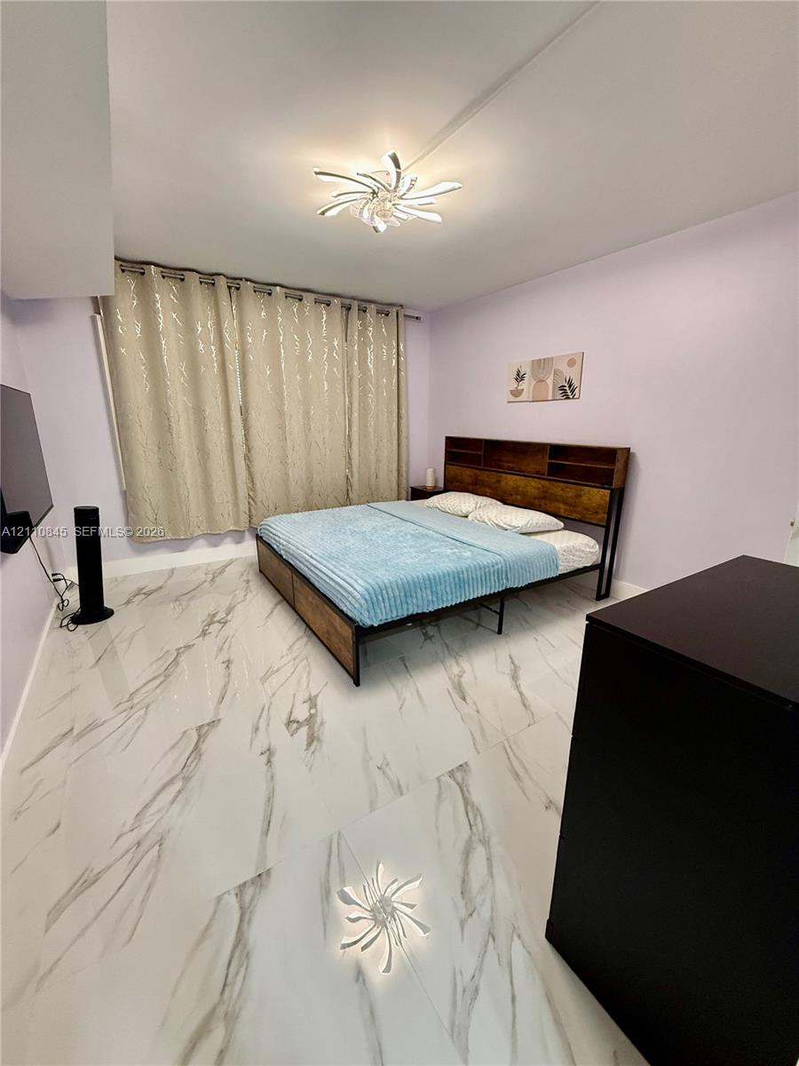 Large-format white tile flooring with grey veining, integrated ceiling-mounted decorative light fixture, and window spanning the length of the wall