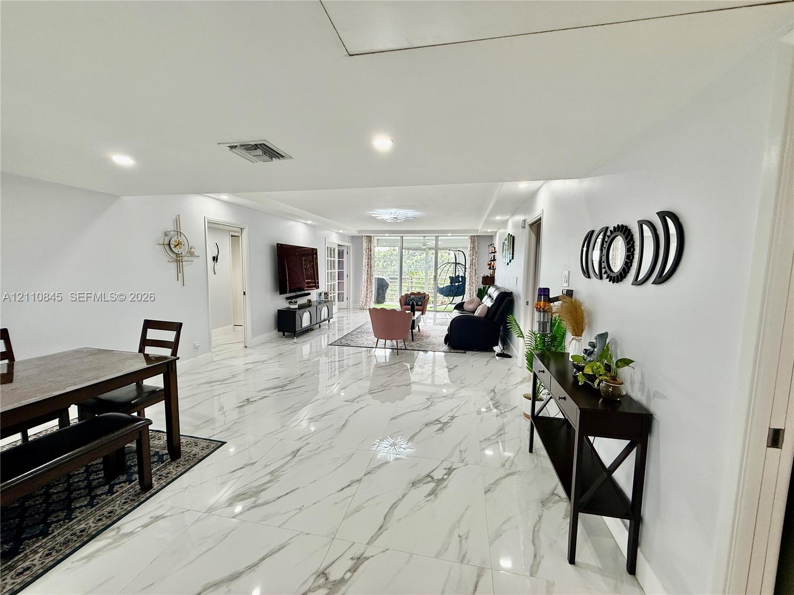Large-format tile flooring, recessed lighting, and expansive glass sliding doors
