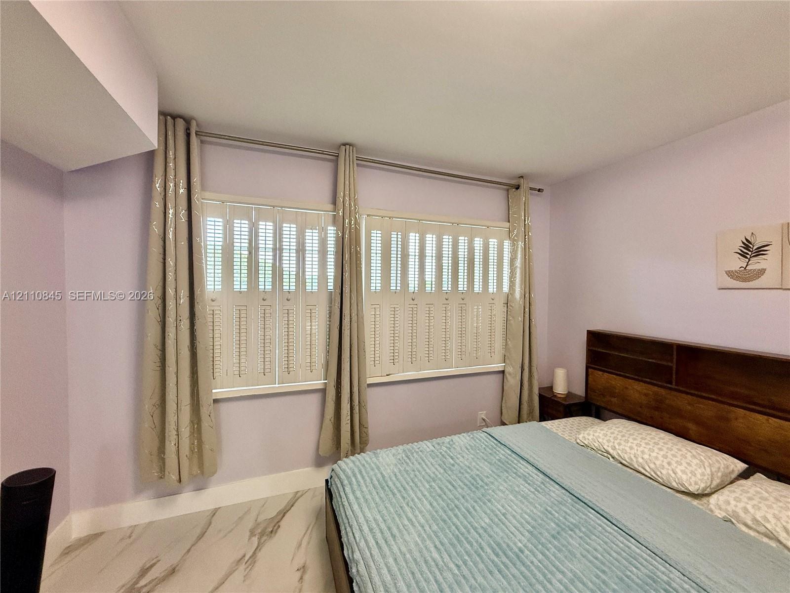 Large windows featuring interior plantation-style shutters and polished stone-finish flooring