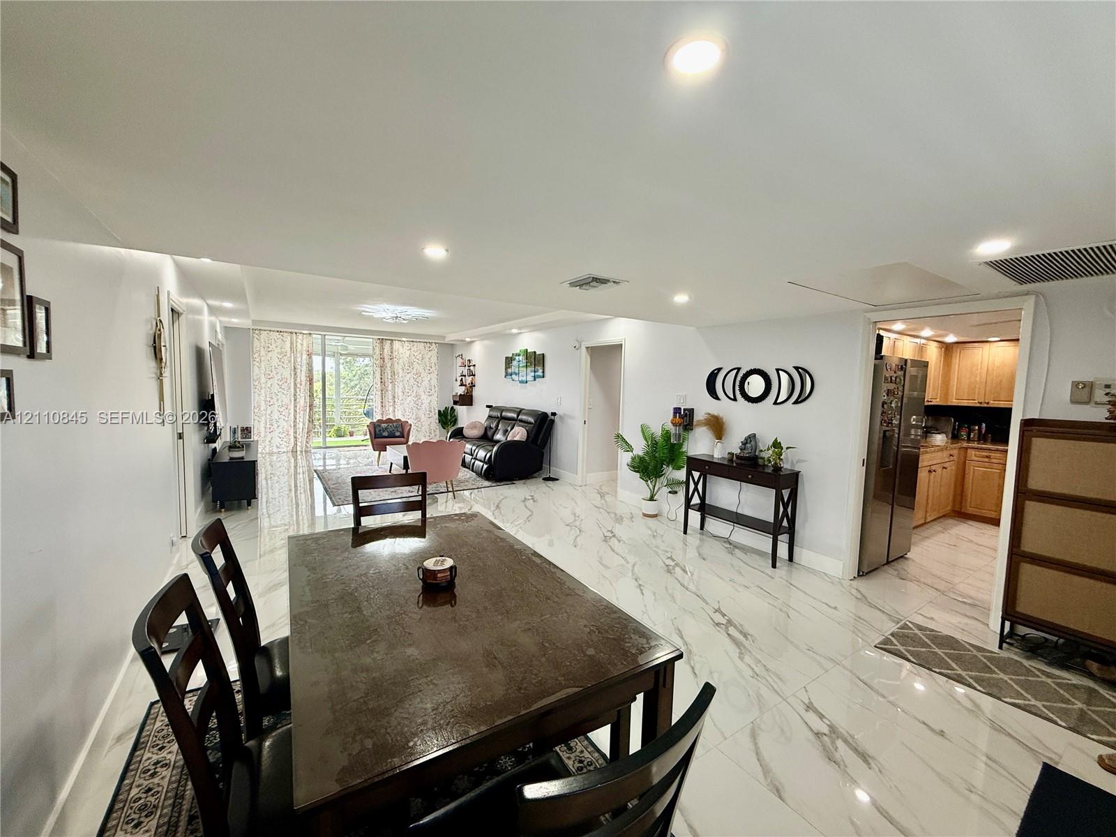Large-format polished tile flooring, recessed ceiling lighting, and sliding glass doors with exterior access