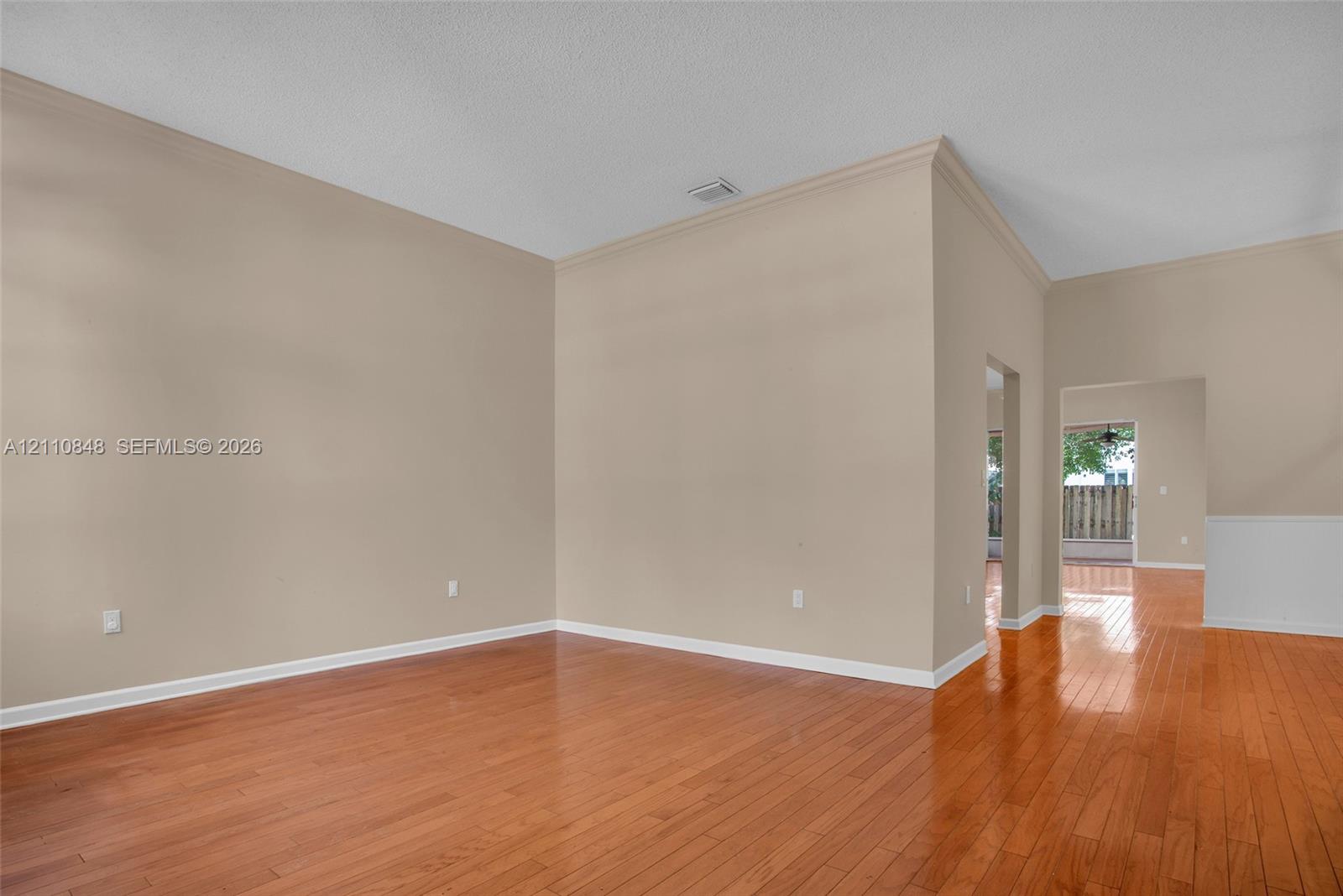 High ceilings featuring crown molding, neutral wall finishes, and polished wood-finish flooring