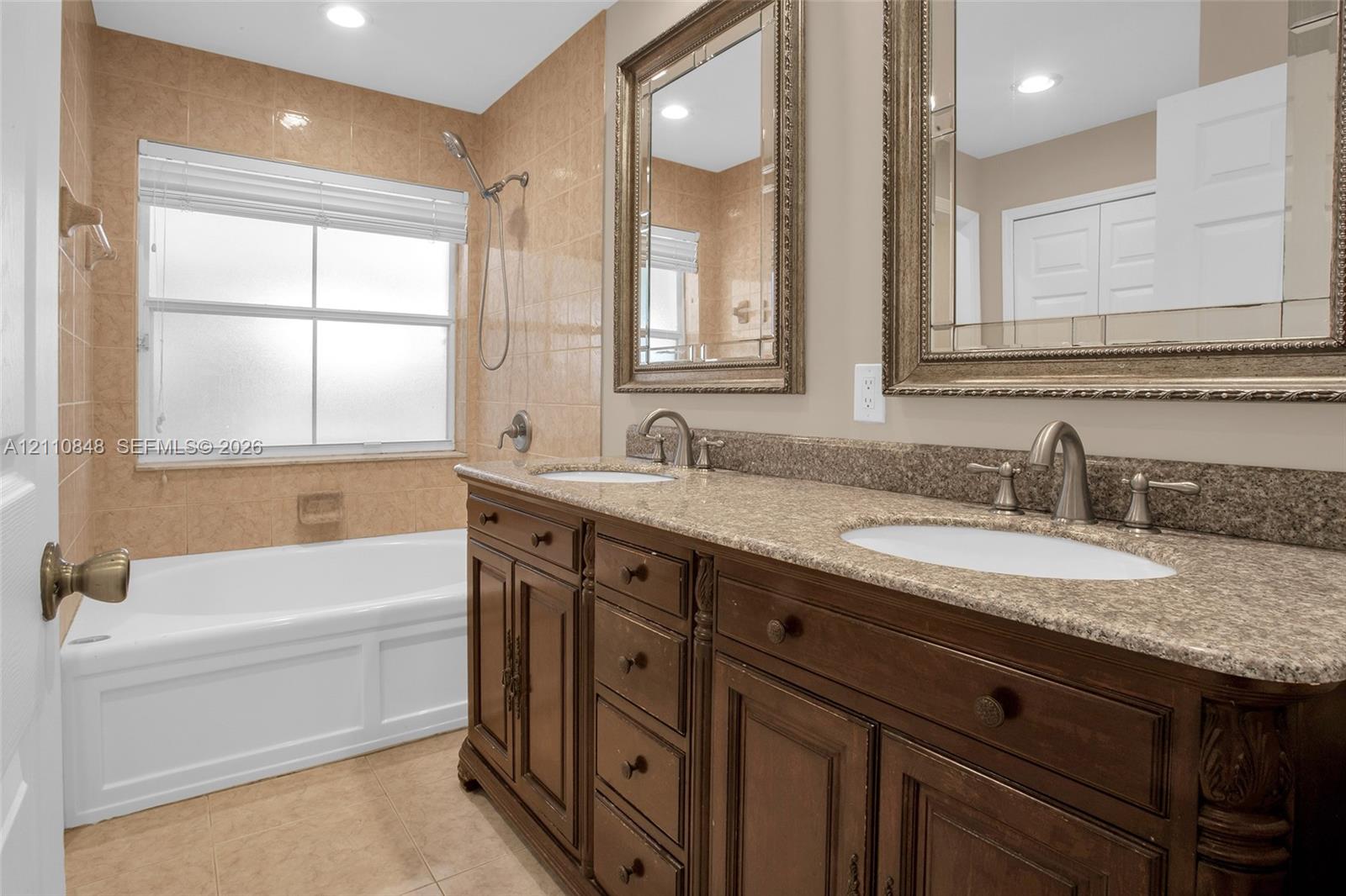 Double vanity with stone-finish countertop, undermount sinks, and decorative framed mirrors