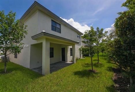 Two-story exterior featuring a covered patio, paved hardscaping, and landscaped green space