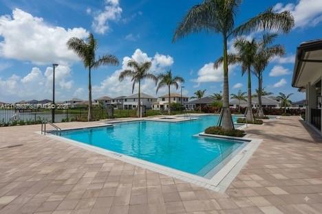 Swimming pool with integrated spa and stone-paver decking, accented by palm trees