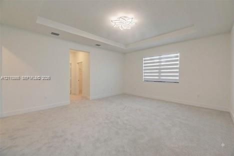 Interior space featuring a tray ceiling, recessed lighting, carpeted flooring, and window shades