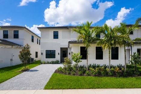 Two-story exterior featuring light-toned smooth stucco finish, horizontal siding accents, dark-framed windows, paver driveway, and professional landscaping with palm trees Two-story exterior featuring light-toned smooth stucco finish, horizontal siding accents, dark-framed windows, paver driveway, and professional landscaping with palm trees