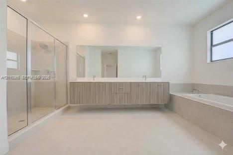Floating vanity with double under-mount sinks, expansive wall-to-wall mirror, glass-enclosed walk-in shower, built-in soaking tub with stone surround, and recessed lighting