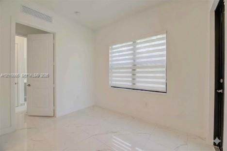 Interior space featuring light-toned stone-finish flooring, dual-panel interior door, banded window shades, and minimalist trim