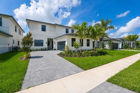 Two-story residence featuring a light-toned exterior, paved driveway, multi-pane windows, attached garage, and landscaped front lawn with palm trees Two-story residence featuring a light-toned exterior, paved driveway, multi-pane windows, attached garage, and landscaped front lawn with palm trees