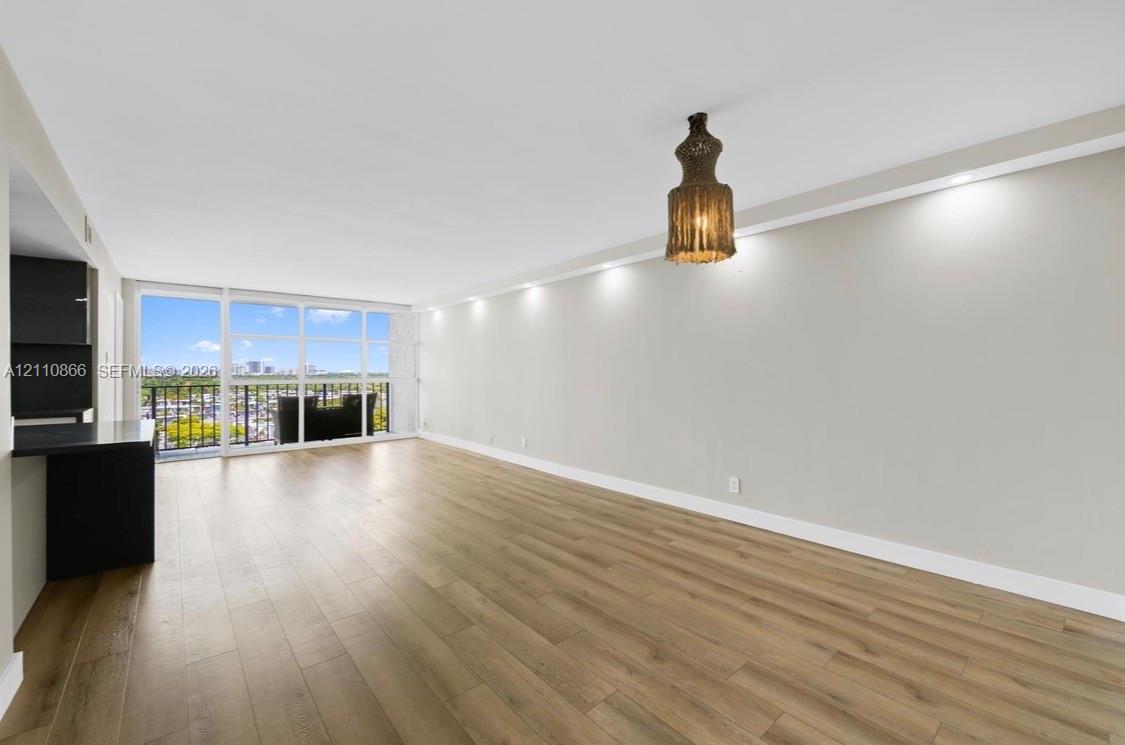 Living area featuring wood-finish flooring, floor-to-ceiling windows, recessed lighting, and a private balcony Living area featuring wood-finish flooring, floor-to-ceiling windows, recessed lighting, and a private balcony