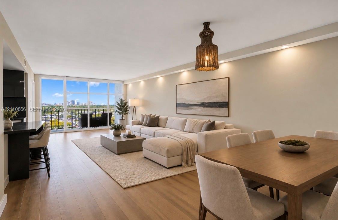 Open-concept living space featuring wood-finish flooring, floor-to-ceiling glass windows, recessed ceiling lighting, a built-in kitchen peninsula, and a woven decorative pendant fixture Open-concept living space featuring wood-finish flooring, floor-to-ceiling glass windows, recessed ceiling lighting, a built-in kitchen peninsula, and a woven decorative pendant fixture