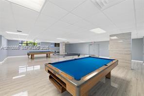 Expansive open-concept room featuring light-toned wood-finish flooring, recessed lighting, and a textured wall accent