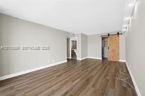 Interior space featuring wood-finish flooring, recessed lighting, and a sliding barn door with matte black hardware Interior space featuring wood-finish flooring, recessed lighting, and a sliding barn door with matte black hardware