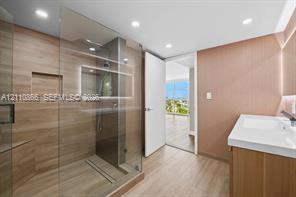 Walk-in shower with wood-finish tile surround, integrated shower niche, glass enclosure, and wood-finish cabinetry with a white countertop Walk-in shower with wood-finish tile surround, integrated shower niche, glass enclosure, and wood-finish cabinetry with a white countertop
