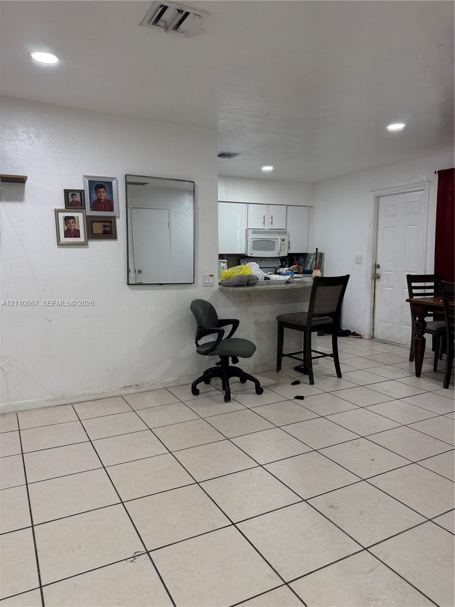 Ceramic tile flooring, recessed lighting, white cabinetry, built-in microwave, and breakfast bar