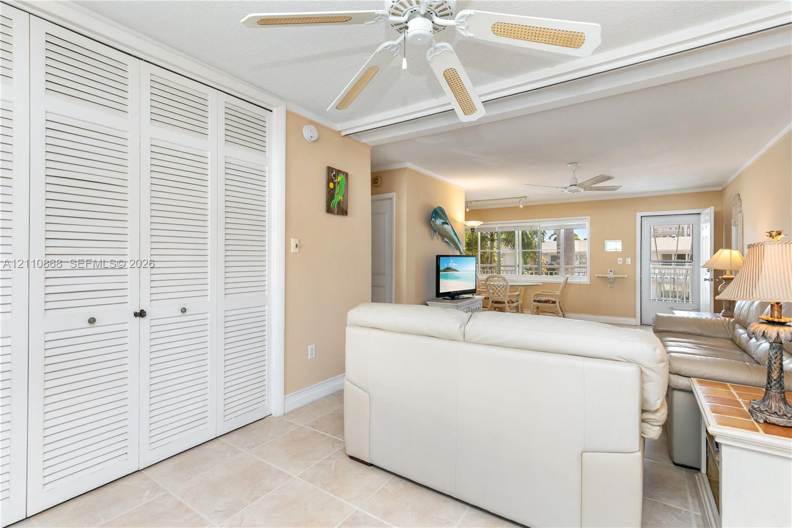 Full-height louvered closet doors, neutral ceramic tile flooring, and dual ceiling fans with integrated lighting