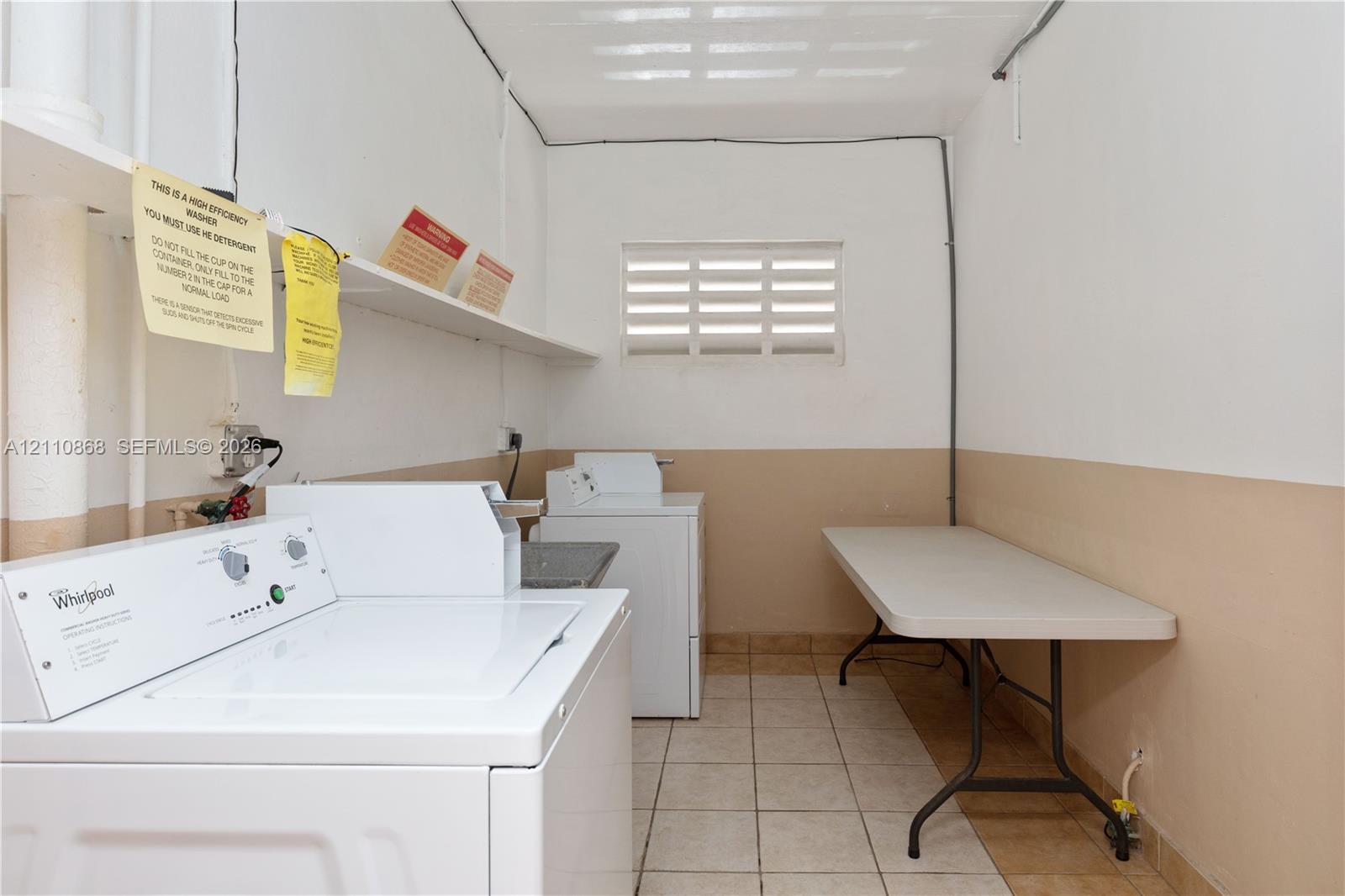 Laundry area featuring ceramic tile flooring, built-in shelving, and a louvered window